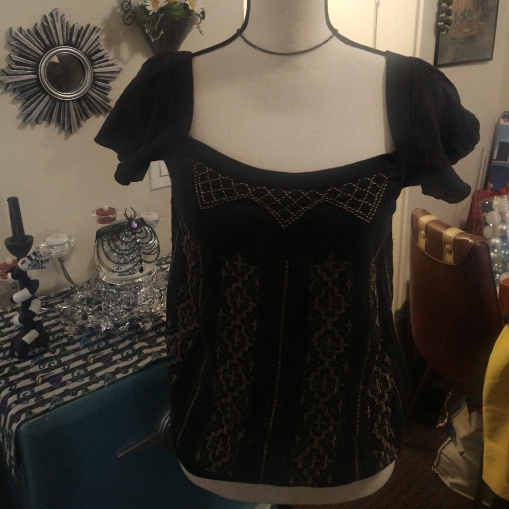 Black top with beige embroidery throughout the front.